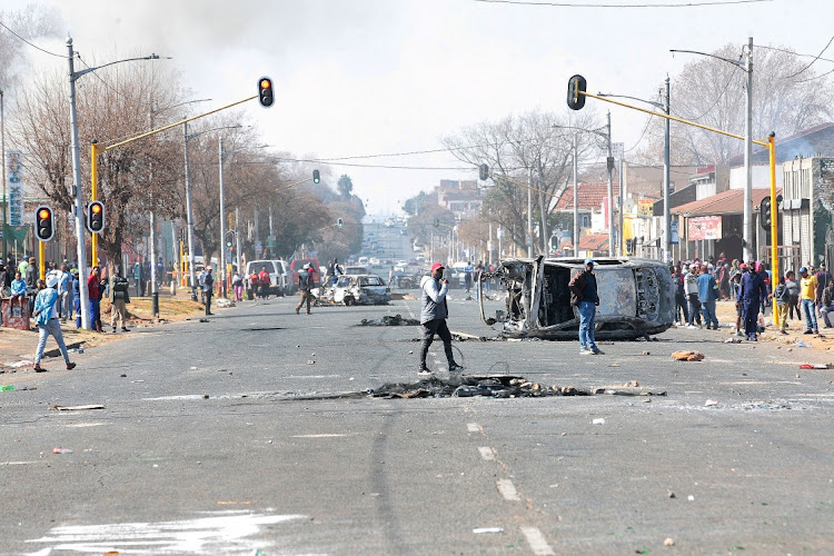 Torched vehicles are shown in Jules Street, Johannesburg, amid protests in response to the imprisonment of former president Jacob Zuma. Picture: VELI NHLAPO