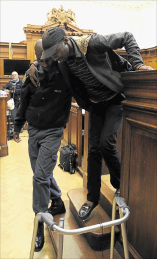 ON TRIAL: Xolile Mngeni, who is appearing in court in connection with the murder of Anni Dewani , is helped out of the dock by a policeman. Photo: Gallo Images