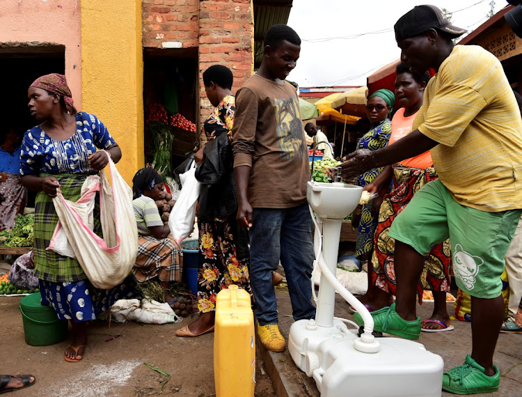 A man washes his hands at a public hand washing station before boarding a bus as a cautionary measure against the coronavirus at Nyabugogo Bus Park in Kigali, Rwanda. March 11, 2020.