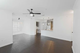 Open concept living, dining, and kitchen areas with white walls and trim, a ceiling fan, and dark wood plank flooring