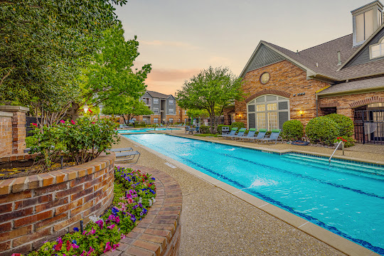 The Seasons at Green Oaks' swimming pool at dusk with lounge furniture