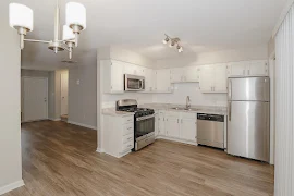 View from corner of dining room with up close view of hanging light fixture and access to the kitchen area