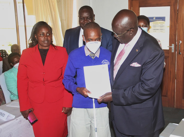 Education CS George Magoha issues a form one selection letter to Mang’era Duncan Christopher who is set to join Thika High School for the blind during the selection launch at Kenya Institute of Curriculum Development in Nairobi on Monday, April 11.