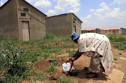 Savanna City resident Sibongile Tshilatshila hustling for a bucket of water from plumbing pipes.