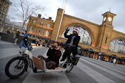 Travellers gesture outside of King's Cross station as the British government imposes a stricter tiered set of restrictions amid the coronavirus disease (Covid-19) pandemic, in London, Britain, December 20, 2020. 