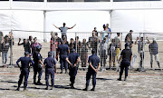 Law enforcement officers in riot gear address homeless residents at the Strandfontein site amidst unrest during a media visit on Thursday.