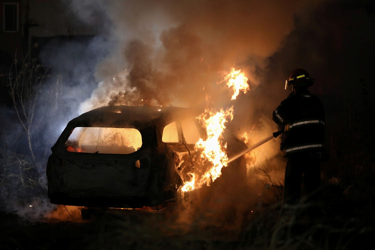 A firefighter tries to put out a fire as a car belonging to Jewish settlers burns amid tension over the possible eviction of several Palestinian families from homes on land claimed by Jewish settlers in the Sheikh Jarrah neighbourhood in East Jerusalem, May 6, 2021.