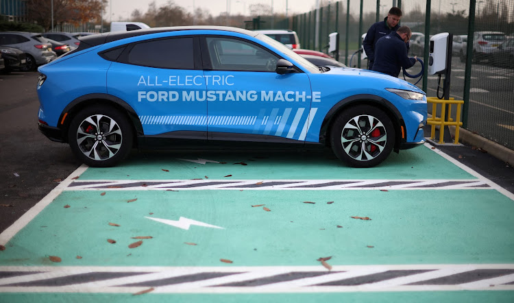 Workers plug in an electric Ford Mustang Mach-e electric vehicle.