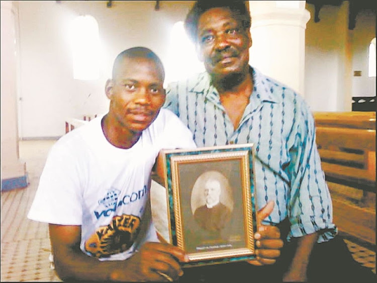 St Matthew’s rector Father William Fobosi, right, and his son Siyabonga, at the church in 2010, holding a portrait of one of the earliest rectors, Rev Charles Taberer