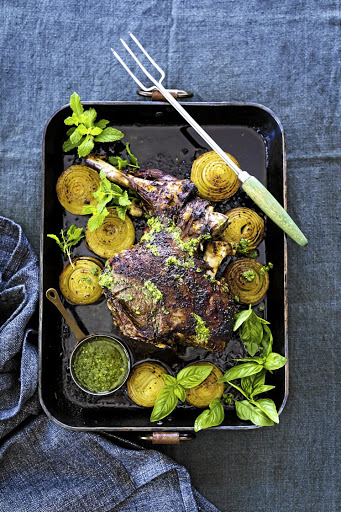 Slow-roasted leg of lamb with roasted onions and chimichurri.