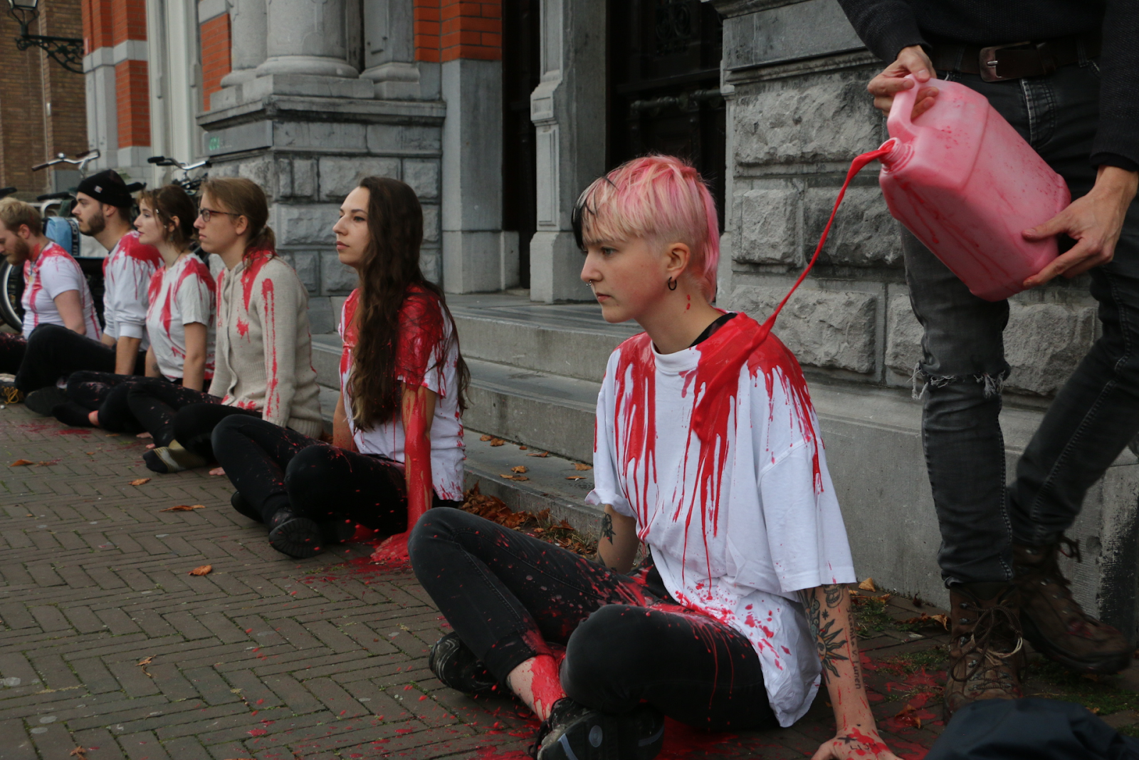 Rebels kneel solemnly in a line as fake blood is poured over them.