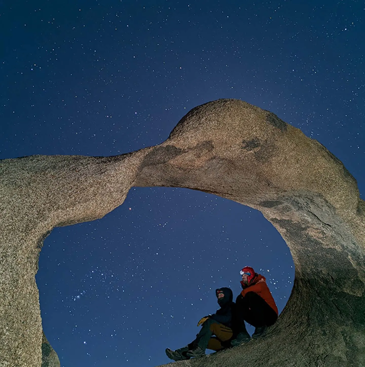 Two hikers sitting in front of a dark sky with stars using Google Pixel's Night Sight
