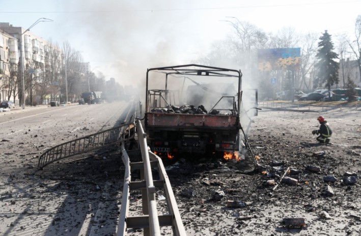 A Ukranian fireman kneels by a damaged vehicle, at the site of a fighting with Russian troops after Russia launched a massive military operation against Ukraine, in Kyiv, Ukraine February 26, 2022