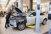 An Audi technician works on an Audi A4. Disclaimer: image captured before implementation of mandated Covid-19 prevention protocols.