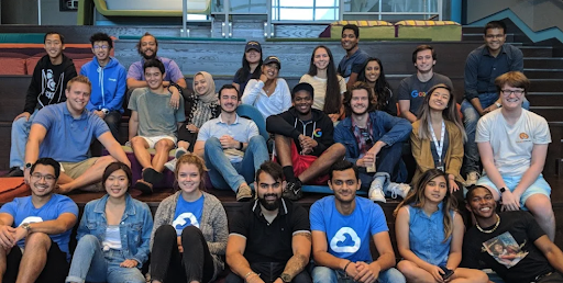 A bunch of students sitting down and smiling at the camera