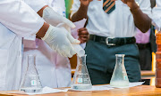 A pupil in uniform watches a science demonstration. Stock photo.