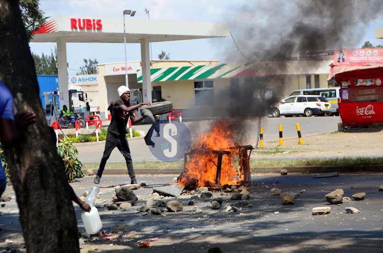 A man fuels a fire by adding a tyre at Kolen along the Nakuru-Eldoret highway in Nakuru Town on July 12, 2023.