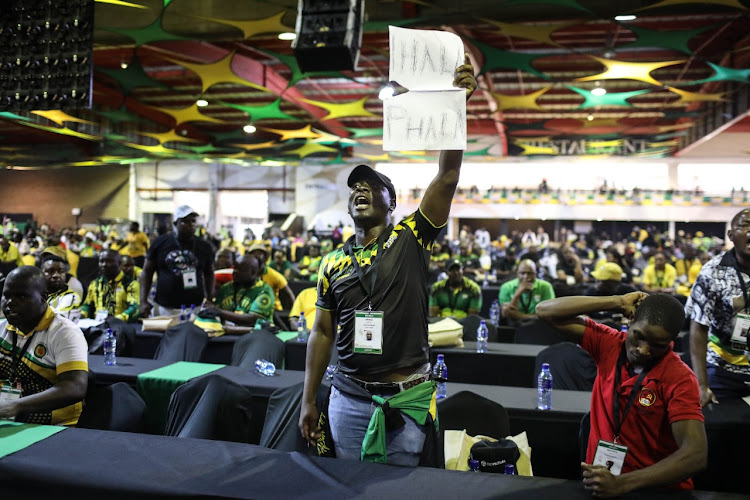 An ANC member holds a sign saying 'Phala Phala' in an attempt to disrupt President Cyril Ramaphosa's opening address at the 55th ANC national conference at Nasrec, Johannesburg, on Friday night.