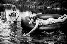 2 meisjes in het water: de een loopt, de ander drijft in een autoband