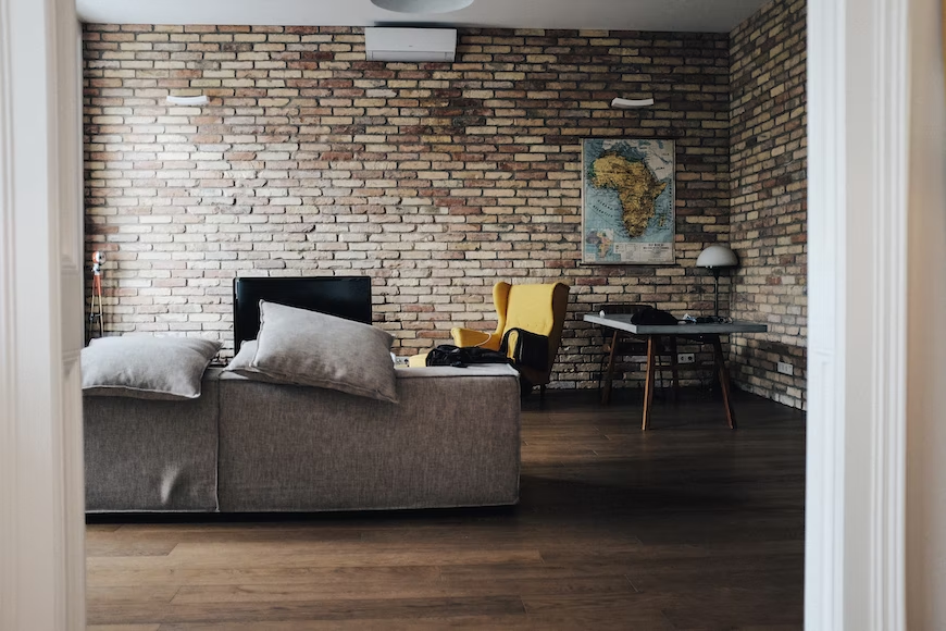 A living room with brown bricks, furniture, and a TV