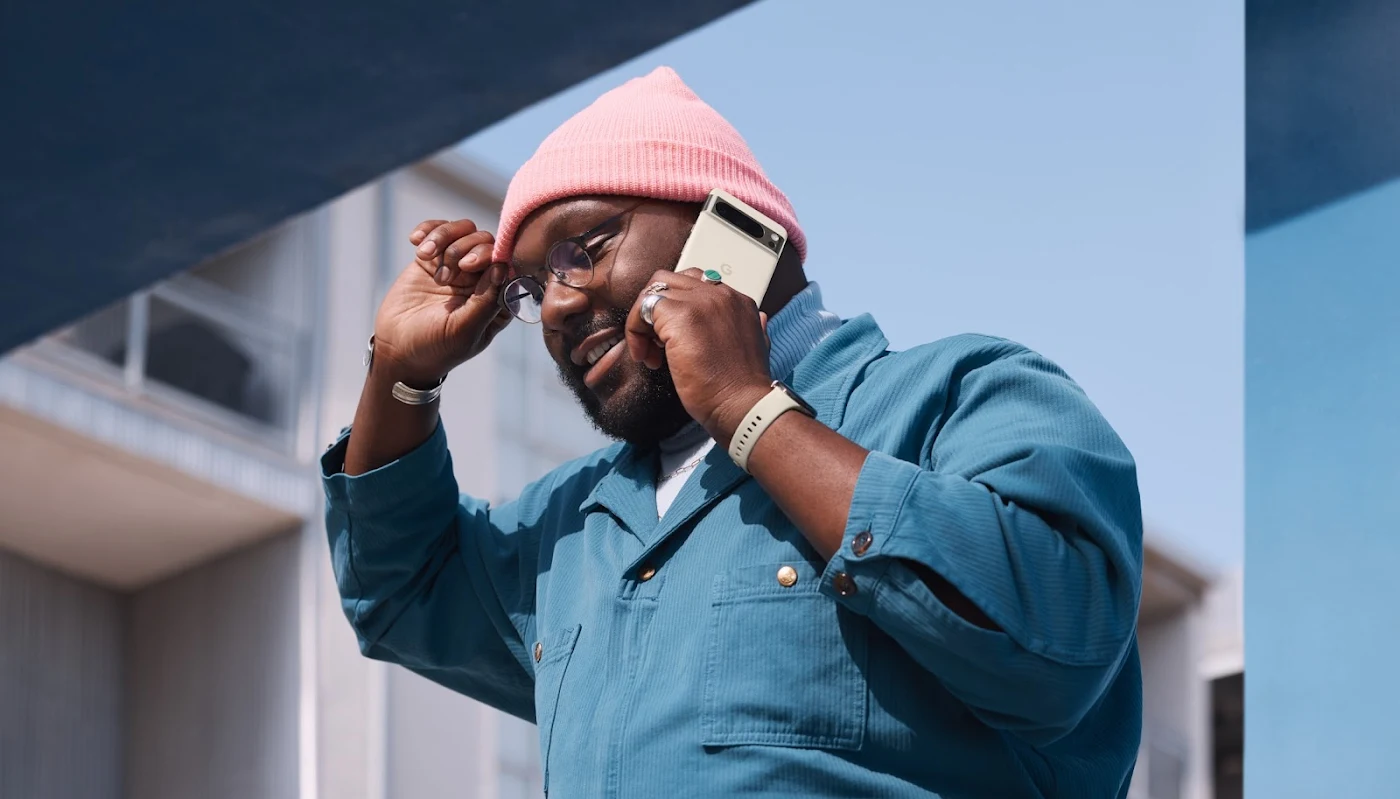 A person holds their Pixel 8 Pro while walking outside.