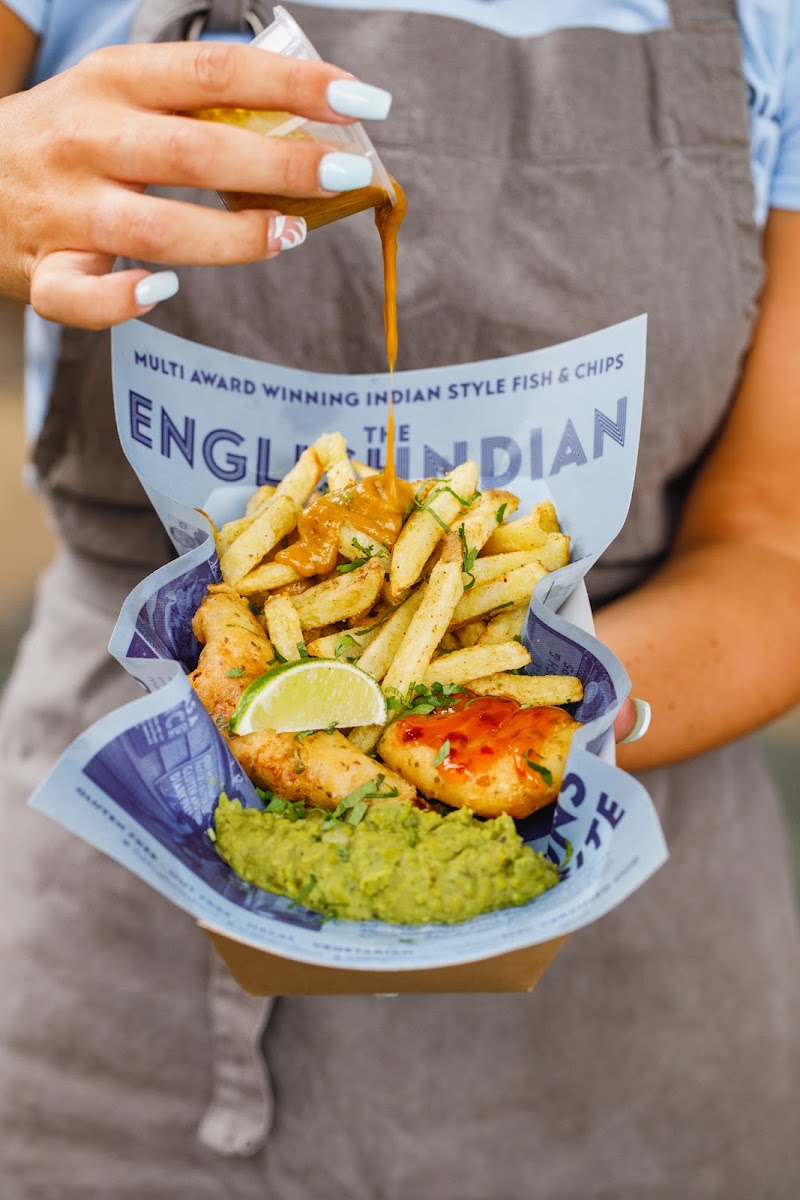 Pakora Battered Fish & Chips, accompanied by our 2 Star Great Taste Award Mint & Chili Garden Mushy Peas, Indian Chip Shop Curry Sauce, Chaat Masala Chips, fresh Lime & Coriander.