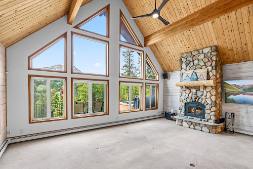 Living room with stone fireplace and large windows in this luxury property for sale in Breckenridge ($1,125,000)