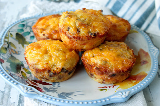 A pile of sausage, egg & cheese coconut flour muffins on a plate.