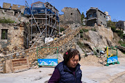 An elder woman walks past a restoration project to protect traditional buildings in Nangan, Taiwan, March 18, 2022. Photo taken March 18, 2022.