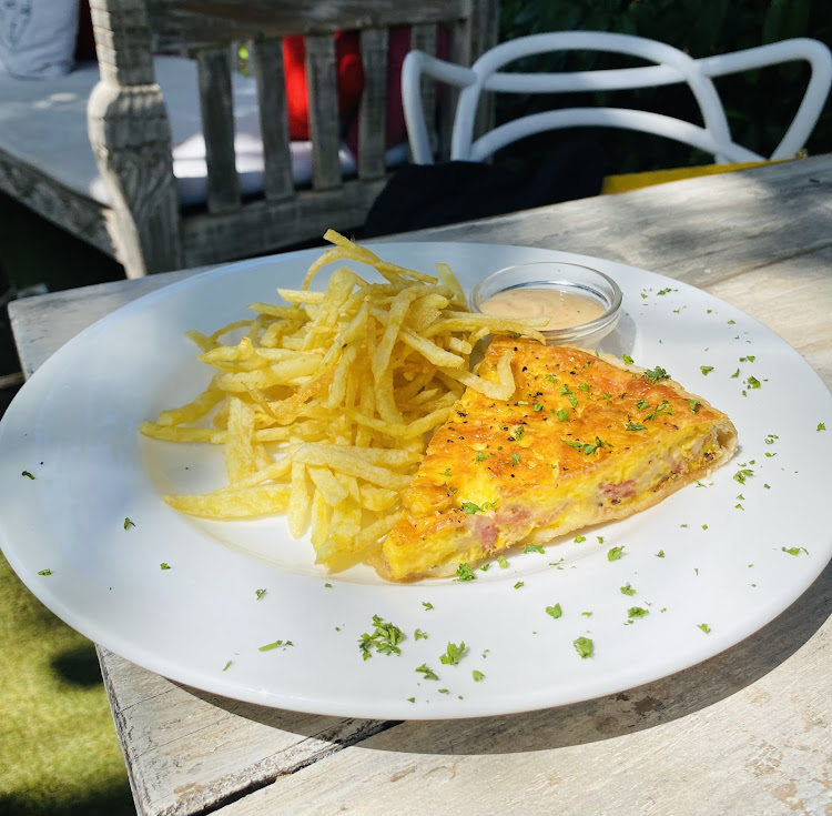 Lorraine quiche served with french fries, dipping sauce and garnished with dill