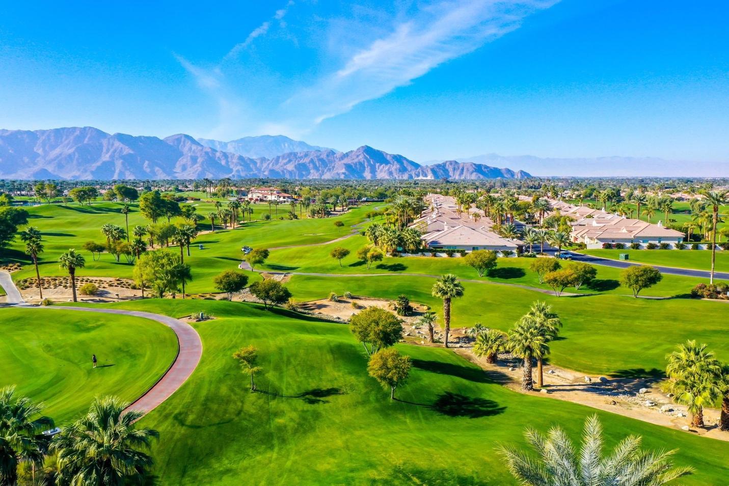 A golf course with trees and mountains in the background Description automatically generated with low confidence