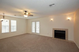 Living area with carpeted flooring, fireplace, and overhead lighting and ceiling fan