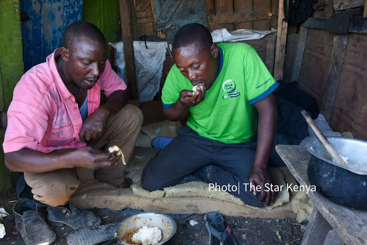 Brian Mutua and Josphat Mwathi share a meal in their shelter at Mukuru Kwa Njenga slums on 22, November 2021 after their house was demolished./ MERCY MUMO