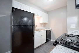 Kitchen with black appliances, white cabinets, stainless steel sink, and dark wood inspired flooring