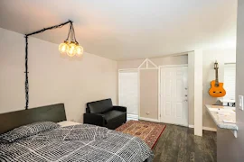 Living area with wood-inspired floors, neutral walls, white trim, view to kitchen with breakfast bar