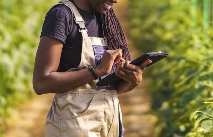 A woman using a tablet in a field, using technology to drive climate issues.