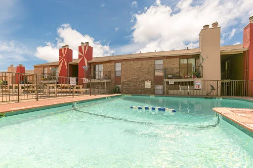 L-shaped pool with a view of two-story apartment building with brown brick exterior and chimneys