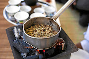 Coffee beans roasting over burning coals.