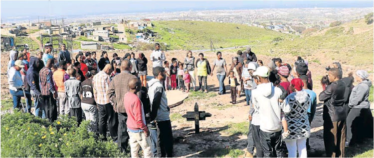 Residents gather to pray and plant a cross on the spot where Anneclato Barendse was shot dead in Helenvale