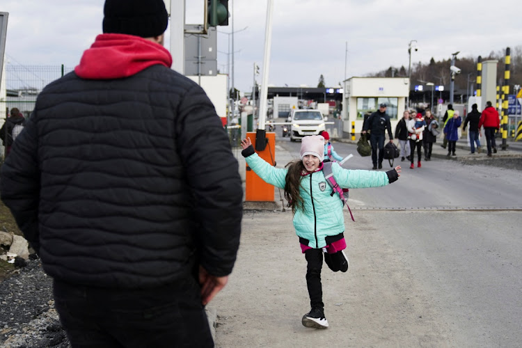 A young Ukrainian girl runs to her father as she exits the border crossing with her siblings and mother after they fled the Russian invasion in Ukraine, in Medyka, Poland.