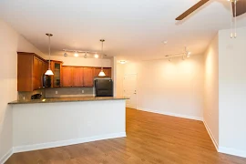 Living and dining areas feature wood-inspired flooring, light walls, white trim, track lighting and a ceiling fan