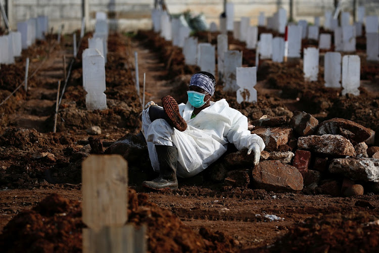 A municipality worker wearing personal protective equipment (PPE) rests at the burial area provided by the government for victims of the coronavirus disease (COVID-19) in Jakarta, Indonesia, June 24 2021.