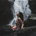 Girl sitting by the waterfall