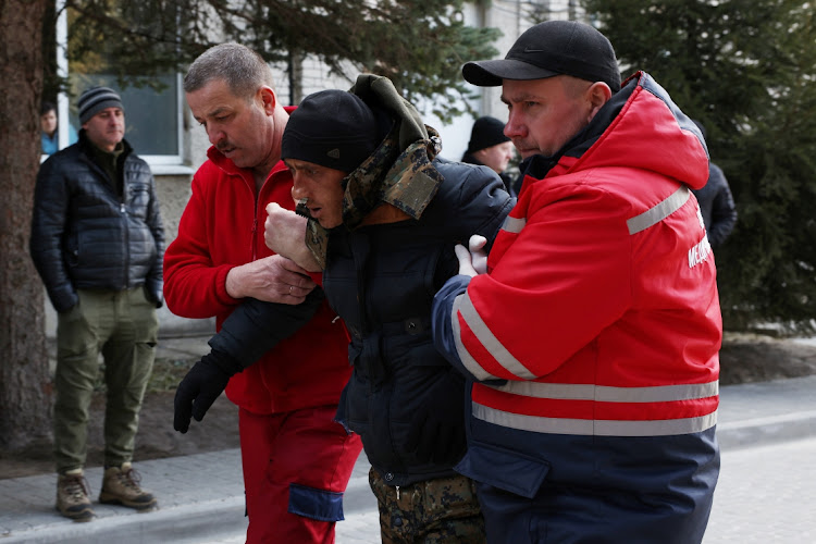 A patient is assisted by medical staff as he arrives at Novoiavorivsk District Hospital on March 13, 2022 in Novoiavorivsk, Ukraine. Early this morning, a series of Russian missiles struck the International Center for Peacekeeping and Security at the nearby Yavoriv military complex, killing at least nine and wounding dozens, according to Ukrainian officials. The site is west of Lviv and mere miles from Ukraine's border with Poland, a NATO member.