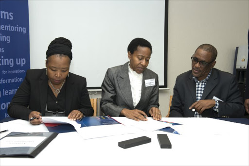 : NMMU Senior Director: Communication and Stakeholder Liaison Lebogang Hashatse (right) looks on as NMMU Deputy Vice-Chancellor: Iinstitutional Support Dr Sibongile Muthwa and iKamvelihle Development Trust founder Dr Lindiwe Msengana-Ndlela sign on the dotted line.