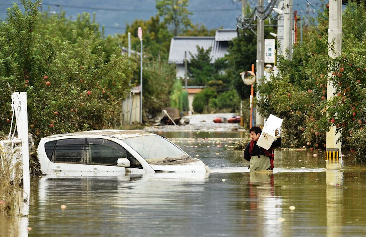 A man wades through floodwaters with items salvaged from his home in the aftermath of Typhoon Hagibis in Nagano on Monday. Tens of thousands of rescue workers are searching for survivors of the powerful typhoon, two days after the storm slammed into Japan, killing at least 35 people. Picture: KUZUHIRO NOGI