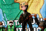 Migrants and members of civil society burn a pinata in the image of US President Donald Trump during a protest against stalled asylum claims and the building of the wall, at the border fence between Mexico and the US, in Tijuana, Mexico, on October 31 2020. 