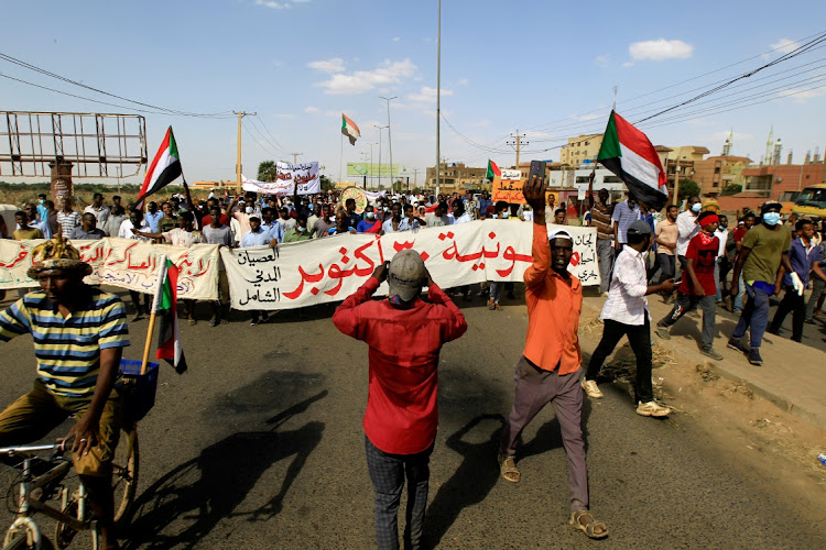 Protesters carry a banner and national flags as they march against the Sudanese military's recent seizure of power and ousting of the civilian government, in the streets of the capital Khartoum, Sudan October 30, 2021.