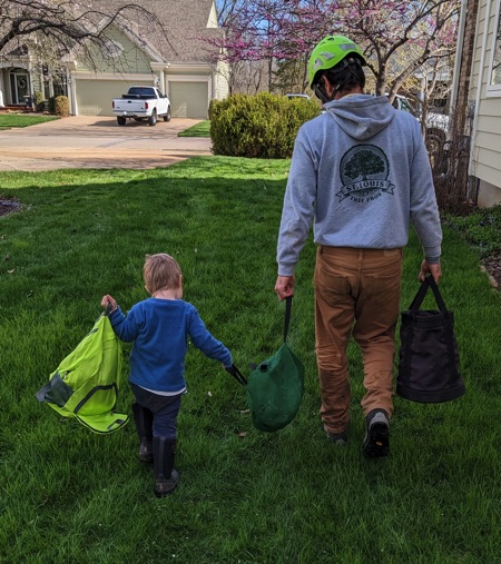 Gabe wate3rhouse and his young apprentice helper collection their gear and taking it to the truck after a successful effort removing the deadwood and trimming the honey locust.