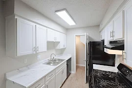 Galley style kitchen with white shaker cabinets, marble inspired countertops, and wood inspired floors